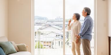 佐賀市街地の住まいを見学する夫婦と明るいマンションの窓辺